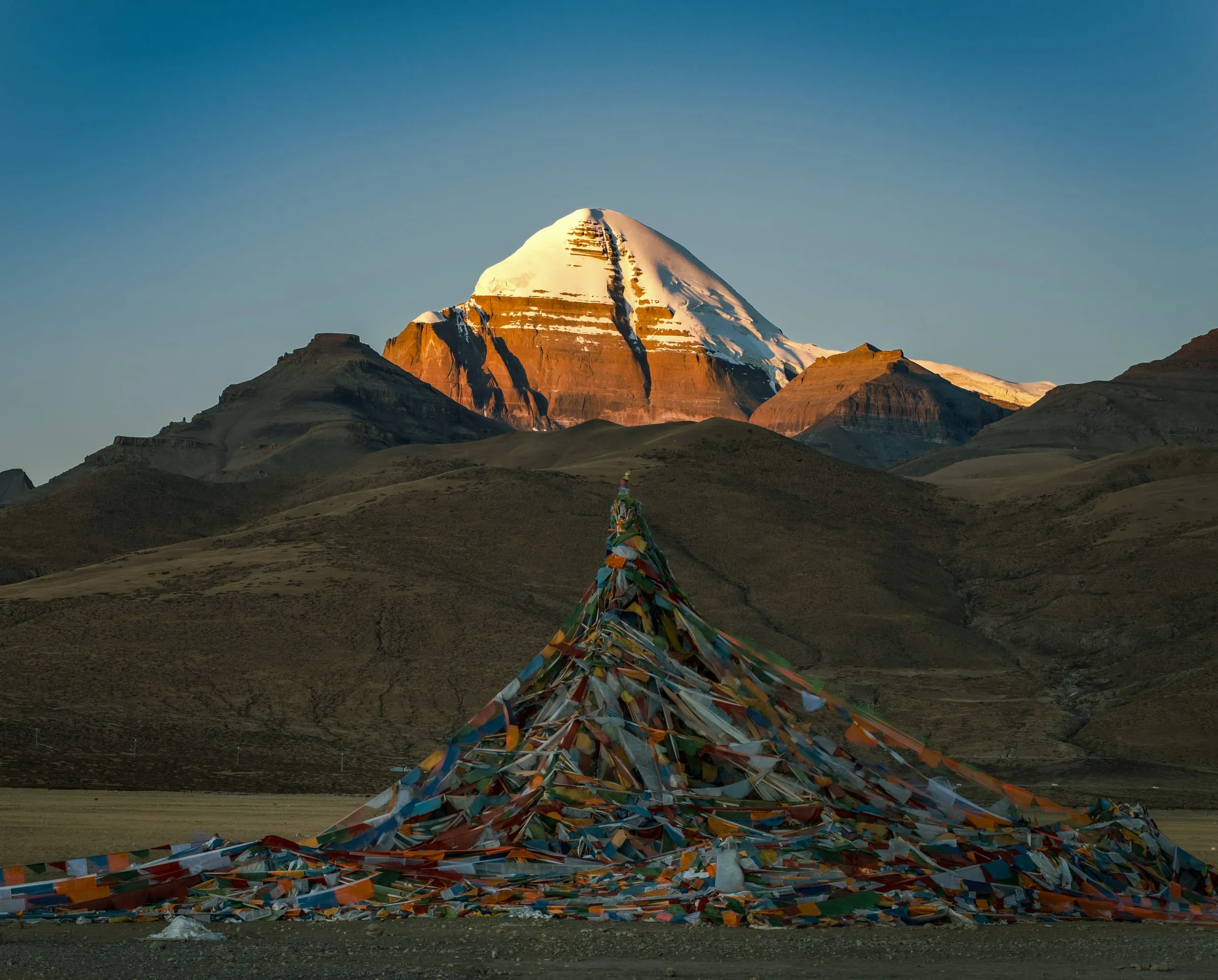 A mountain peak at sunset above prayer flags